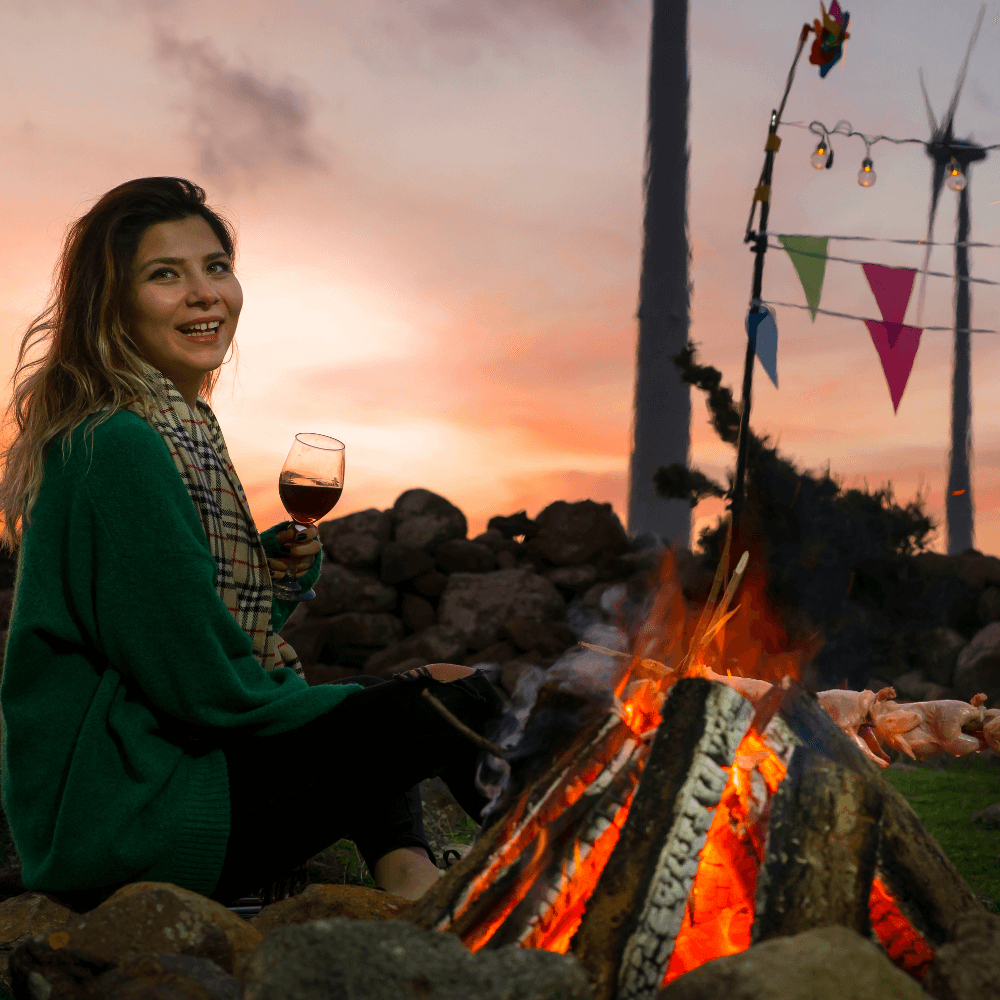 A woman drinking cocktail next to campfire