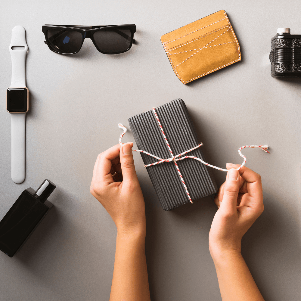 Flat lay of gifts for men including a watch, sunglasses, cologne, wallet and gift box