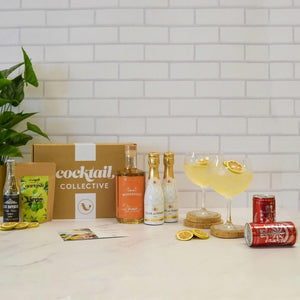 Gin Subscription box in the kitchen with ingredients and 2 Orange Spritz cocktails garnished with lime wheels | Cocktail Collective