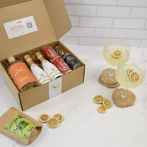 Gin Subscription box in the kitchen with ingredients and 2 gin cocktails garnished with lime wheels | Cocktail Collective