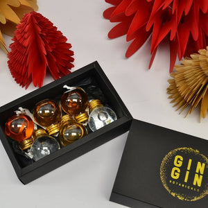 Set of 6 mixed spirut filled baubles nestled into box surrounded by christmas trees