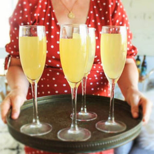 Lady in a polka dot dress holding 4 French 75's on a tray