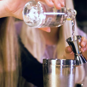 Girlo pouring gomme syrup into a spirit measure