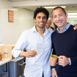 Men posing with cocktails in hands at office drinks