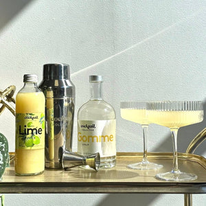 The Cocktali Staples Kit displayed on a bar cart with cocktails in ribbed cocktail coupes