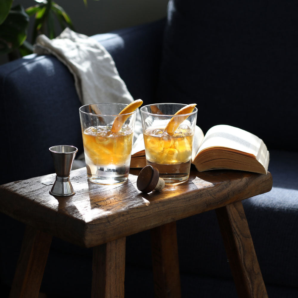 Two Bourbon Old Fashioned cocktails on a side table