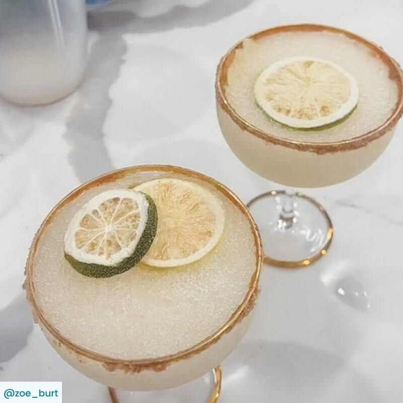Two Margarita cocktails with lime wheel garnish and salted rim on glasses