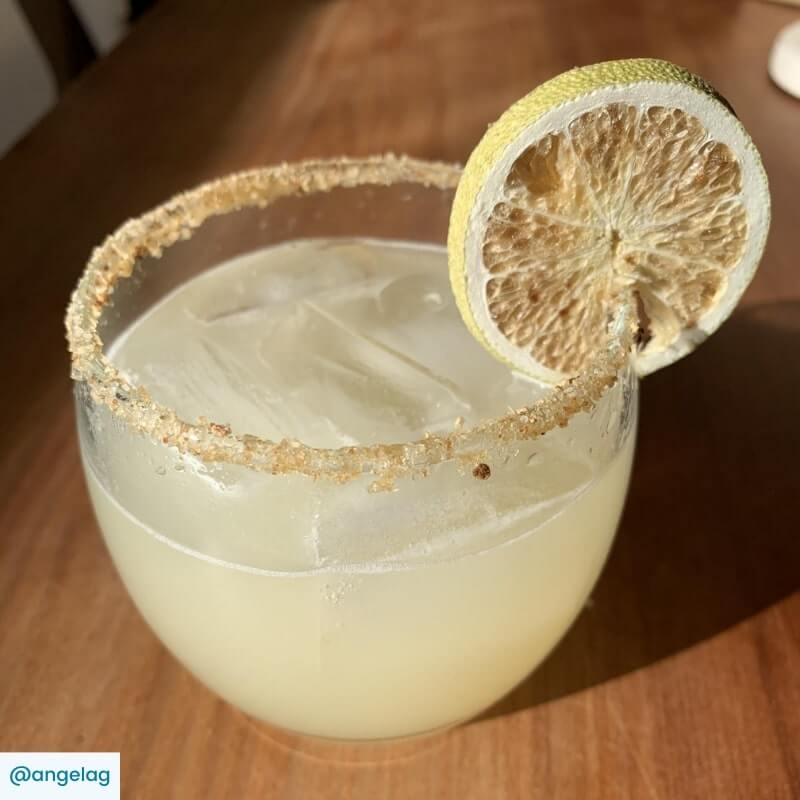 A Margarita cocktail in a tumbler with a chili salt rim and lime wheel garnish