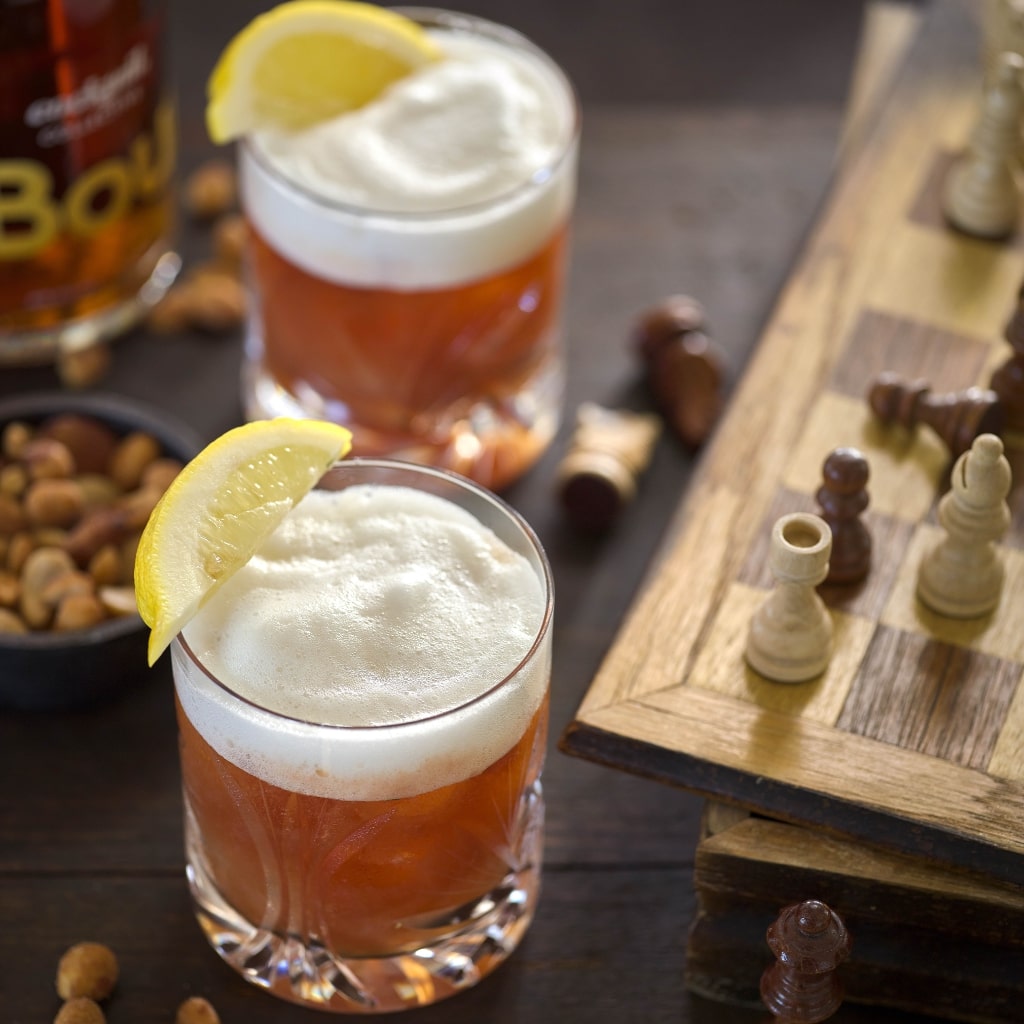 Whiskey Sour cocktails with garnish and chess board