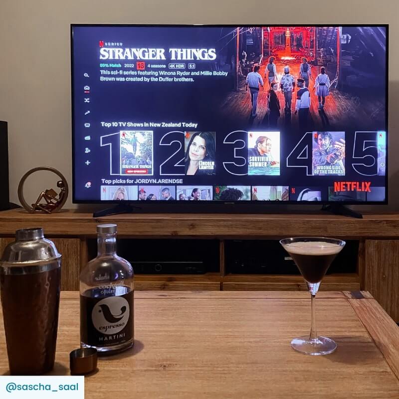 Espresso Martini cocktail, bottle and shaker on table with Netflix