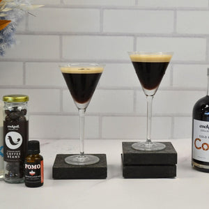 Two Espresso Martini cocktails with Fomo and a jar of chocolate coated coffee beans from Cocktail Collective.