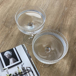 Ribbed cocktail coupe glasses filled with water on a table top