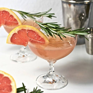 Two Blush Martini cocktails garnished with blood orange and rosemary 