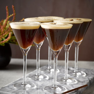 Six fluffy Espresso Martini cocktails garnished with coffee beans in long stemmed Schott Zwiesel Martini glasses