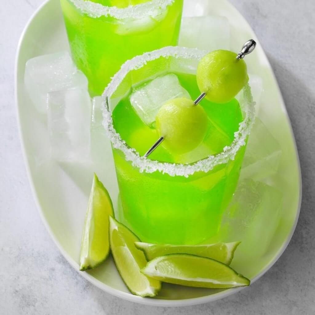 Melon Margarita with lime wedges and melon balls by Cocktail Collective 