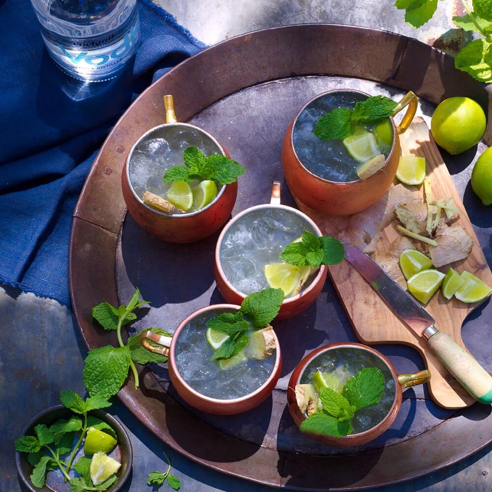 A gift set with the Moscow Mule Cocktail Kit with Vodka, Ginger Beer, Lime Juice, Gomme Syrup and four copper mugs