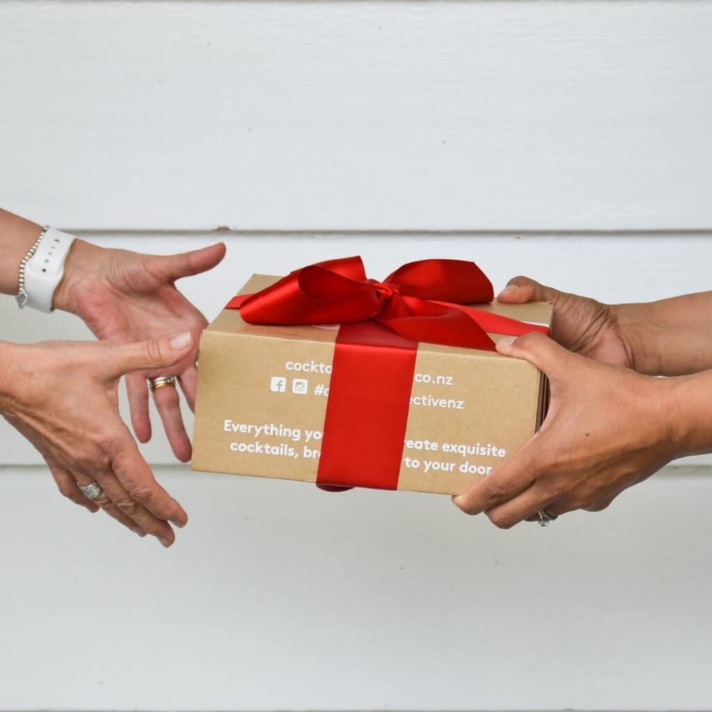 Hands giving and receiveing a Cocktail Collective giftbox