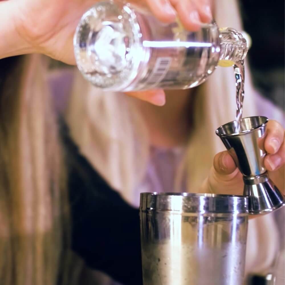 Girlo pouring gomme syrup into a spirit measure