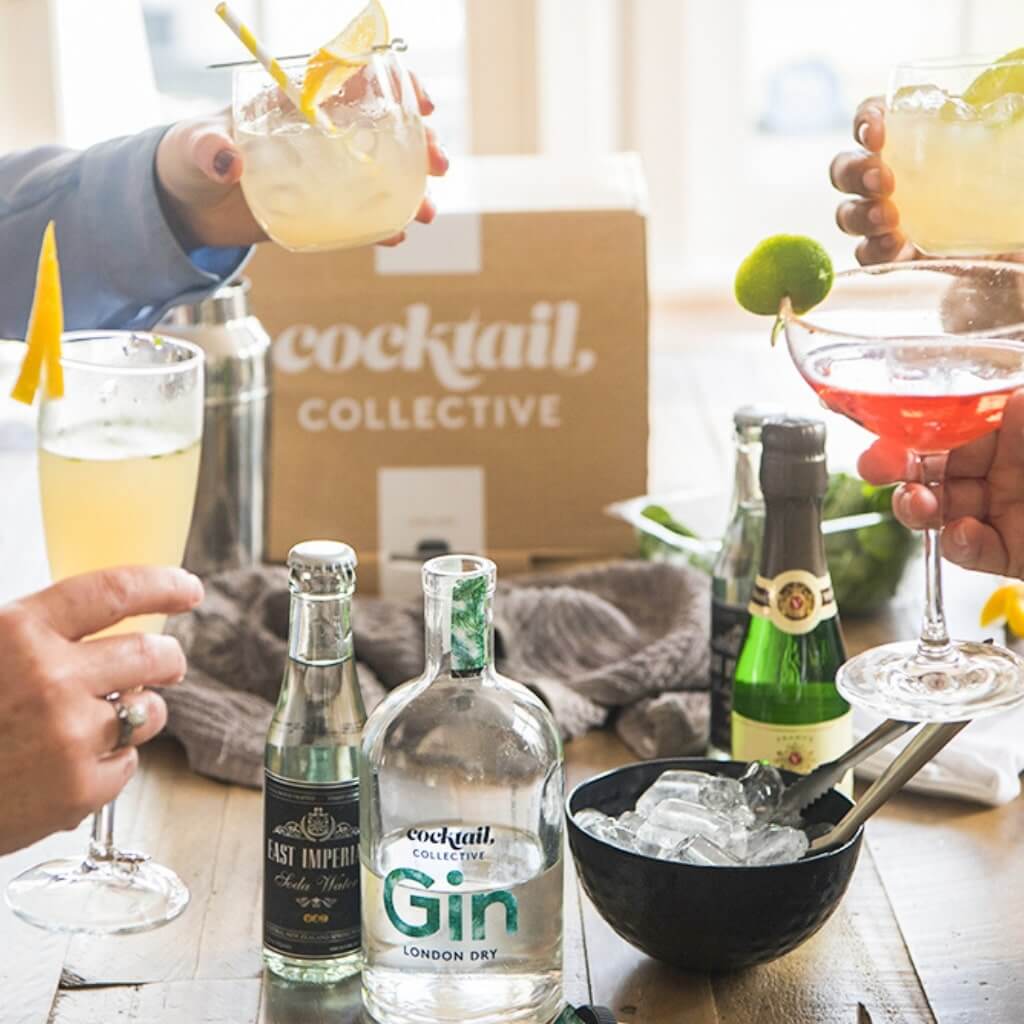 Women cheers at table with variety of cocktails in hands