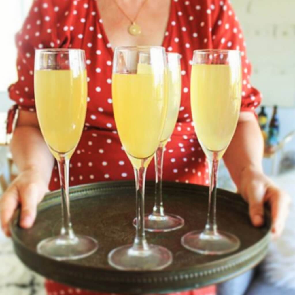 Dutch75 cocktails on a tray carried by a woman