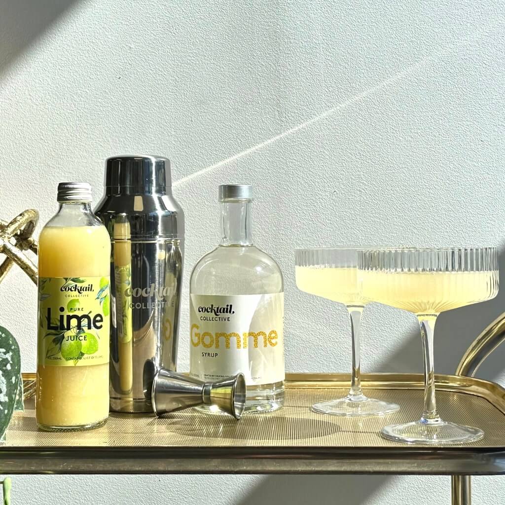 The Cocktali Staples Kit displayed on a bar cart with cocktails in ribbed cocktail coupes