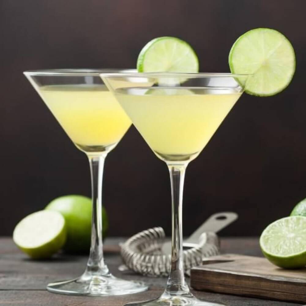 Two Kamikaze cocktails garnished with a lime wheel on a dark kitchen bench